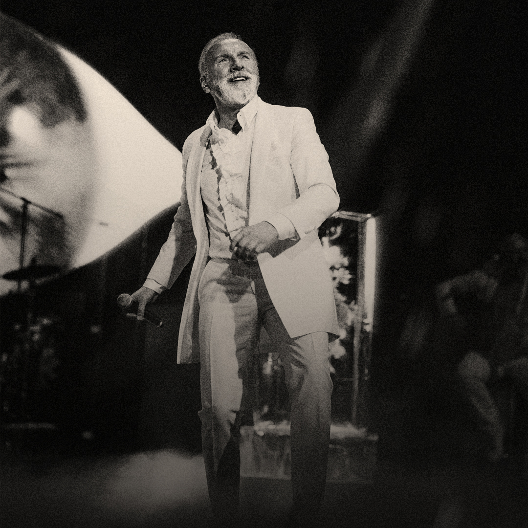 Black-and-white photograph of a singer holding a microphone on stage